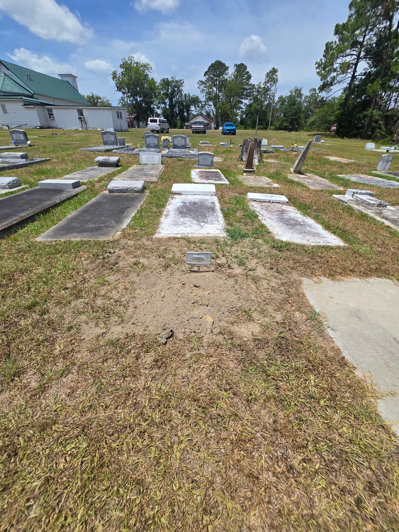 Live Oak Missionary Baptist Church, white clapboard under a green roof, beside its cemetery on a blue-sky Georgia day